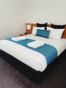 a large bed with white and blue sheets and pillows at Red Earth Motel in Broken Hill