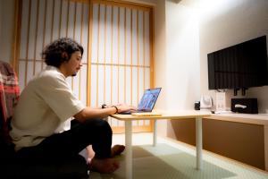 a man sitting at a table with a laptop computer at Hotel S-Presso Namba in Osaka