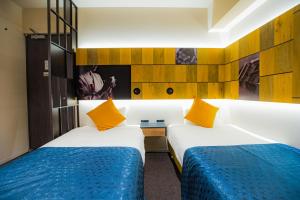 2 camas en una habitación de hotel con almohadas amarillas en Hotel S-Presso Namba, en Osaka