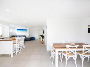 a white kitchen and dining room with a table and chairs at Sandy Feet Retreat I Pet Friendly I 1 Min Walk to Beach in Currarong
