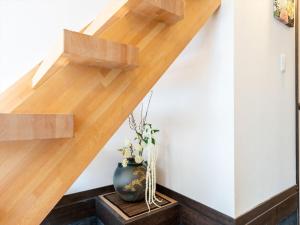een houten trap met een vaas op een tafel bij YADOYA Ryusenjicho in Tokyo