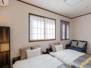 een slaapkamer met 2 bedden en een blauwe stoel bij YADOYA Ryusenjicho in Tokyo