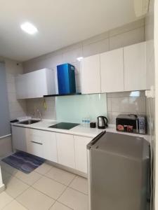 a kitchen with white cabinets and a sink and a refrigerator at Conezion Residence Putrajaya nearby IOI City Mall in Putrajaya