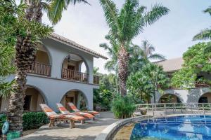 a villa with a swimming pool and palm trees at Coconut Lodge Resort in Jepara