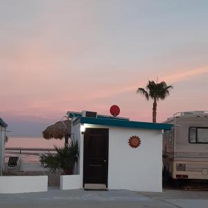 un piccolo edificio bianco con una porta nera e una palma di #7 Beach Front Private Room a San Felipe