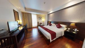 ein Hotelzimmer mit einem Bett und einem Flachbild-TV in der Unterkunft Tara Angkor Hotel in Siem Reap