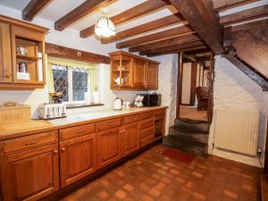 a large kitchen with wooden cabinets and a window at Nant Cottage in Llanrwst