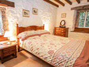 a bedroom with a bed and a table and a clock at Nant Cottage in Llanrwst