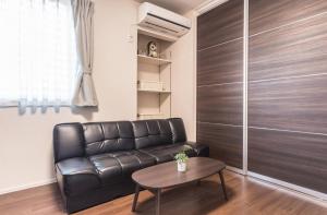 ein Wohnzimmer mit einem Ledersofa und einem Tisch in der Unterkunft T-BASE - Vacation STAY 21952v in Tokio