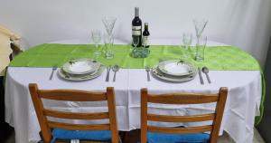 Buenaventura Cosy Apartment kato Paphos في Paphos: طاولة مع مفرش أبيض وكراسي وزجاجات نبيذ