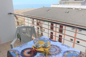 uma mesa com duas chávenas e um prato numa varanda em Beach front apartment with sea view - Beahost em Bibione
