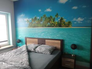 a bedroom with a bed with a painting of a beach at Yakuzza Apartments in Giżycko