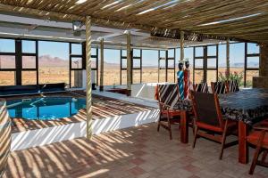 a patio with a table and chairs and a swimming pool at Mountain View Villa in Maltahöhe