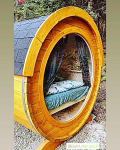 ein Holzbett in einem hölzernen Kreis mit einem Fenster in der Unterkunft Beczki Pod Lasem in Trzemeśnia
