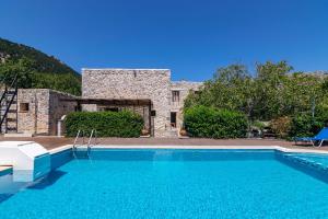 a swimming pool in front of a stone house at Archodiko Villa Imbros in Ímbros