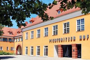 um grande edifício amarelo com um telhado vermelho em Piesteritzer Hof - Hotel Garni em Wittenberg