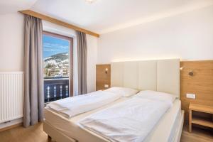 een slaapkamer met een groot bed en een groot raam bij Rosalpina Apt 3 in San Vigilio Di Marebbe