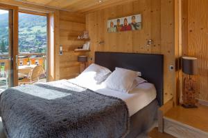 a bedroom with a bed and a large window at Chalet-Hotel et Spa Le Delta in Le Grand-Bornand