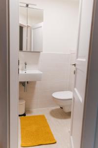 a bathroom with a toilet and a sink and a yellow rug at Guest House Rosemary in Piran