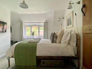 a bedroom with a large white bed with a green blanket at Kings Cottage - Heart of the Deverills in Warminster