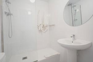 a white bathroom with a sink and a mirror at Hostal Hera in Barcelona