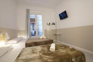 a hotel room with two beds and a tv on the wall at Hostal Hera in Barcelona