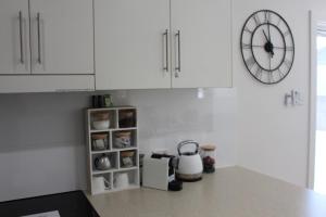 a kitchen with white cabinets and a clock on the wall at Annie's Apartment in Mount Gambier