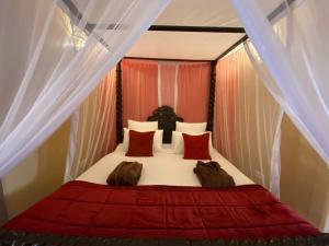 - une chambre avec un lit doté de rideaux rouges et blancs dans l'établissement Jafferji House, à Zanzibar City