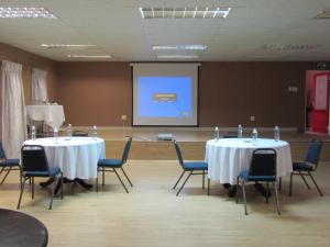 a meeting room with two tables and chairs and a screen at THE CLAN LODGE in Mohlanapeng