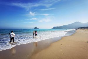 two people standing in the water on a beach at Shenzhen Xichong beach Lanting Homestay in Dapengcheng
