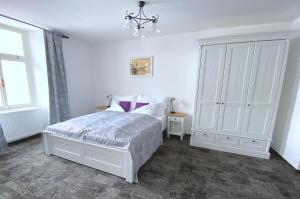 - une chambre blanche avec un lit et un lustre dans l'établissement Penzion U Anděla, à Jičín