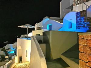a group of white buildings with blue lights on them at Aqua & Terra Traditional Cave Houses in Oia +109 photos