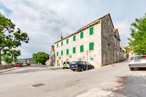 a large stone building with green windows on a street at Apartment Magdalena in Nerežišće