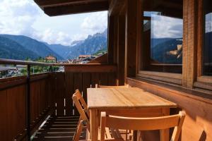 a wooden table and chairs on a balcony with mountains at Mansarda vista lago in Auronzo di Cadore +29 photos