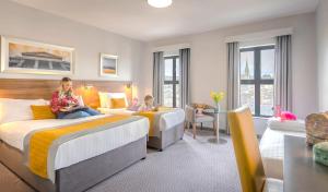 2 filles assises sur les lits d'une chambre d'hôtel dans l'établissement Maldron Hotel Derry, à Derry Londonderry