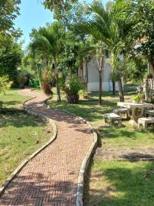 a brick path in a park with trees and benches at บ้านพักคุณยายเขียว in Ban Thung Kham