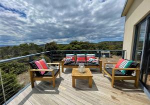 a deck with chairs and tables on a balcony at Freycinet Dream in Coles Bay