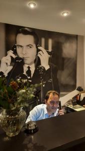 a man sitting in front of a mirror talking on a phone at Akteon Hotel in Stuttgart