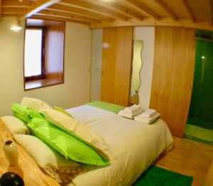um quarto com uma cama com lençóis verdes e uma janela em Casa do Castanheiro - Eido do Pomar em Arcos de Valdevez