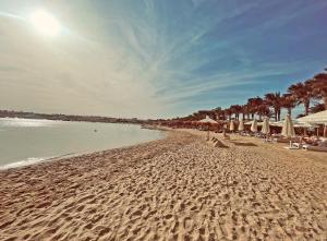 a sandy beach with umbrellas and chairs and the ocean at Sunrise Tucana Resort -Grand Select in Hurghada