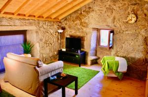 a living room with a couch and a tv at Casa do Castanheiro - Eido do Pomar in Arcos de Valdevez