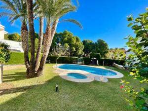 a swimming pool in a yard with a palm tree at Arenda Pino Alto PLAYA2 in Hospitalet de l'Infant