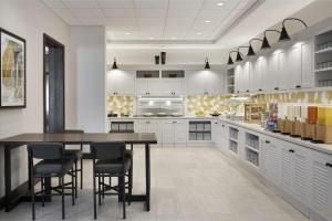 una cucina con mobili bianchi, tavolo e sedie di Hyatt Place Evansville a Evansville