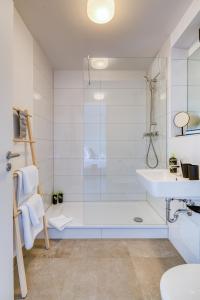 baño blanco con ducha y lavamanos en limehome Garching bei München en Garching bei München
