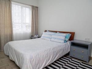 1 dormitorio con 1 cama con mesita de noche y ventana en Nyumba Nzuri 2 bedroom apartment central of NBO, en Nairobi