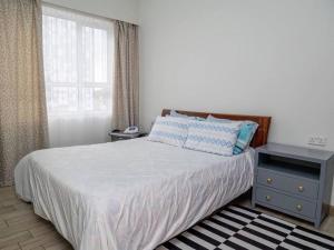 a bedroom with a bed with a nightstand and a window at Nyumba Nzuri 2 bedroom apartment central of NBO in Nairobi