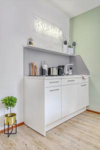 a kitchen with white cabinets and a shelf at limehome Garching bei München in Garching bei München