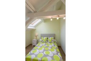 1 dormitorio con 1 cama con lunares amarillos y verdes en Chez Germaine, en Saint-Romain