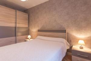 ein Schlafzimmer mit einem weißen Bett und zwei Lampen in der Unterkunft Maison Picard in Saint-Romain