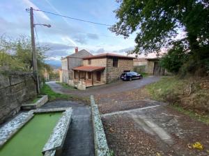 una vista desde la calle de una casa con un estanque en Apartamentos Rurales A Torre, en Santa María